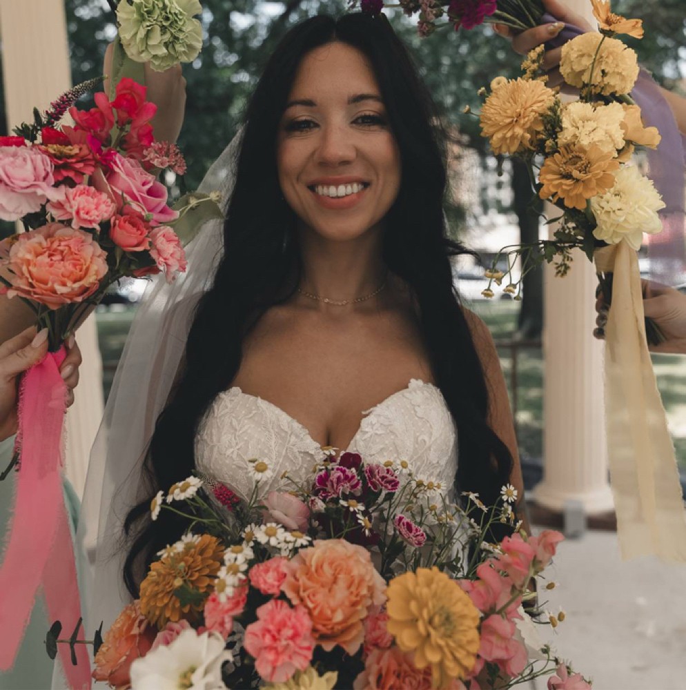 Smiling bride with a colorful bouquet, makeup by Bryanna